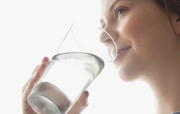 A woman drinking a glass of clean water filtered by Berkeys. 
