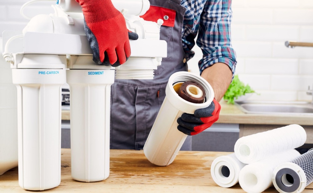 Man changing filter on reverse osmosis filtration system