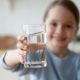 Smiling young girl holding up glass of clean, filtered water