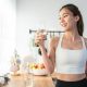 Young woman drinking water after exercising at home